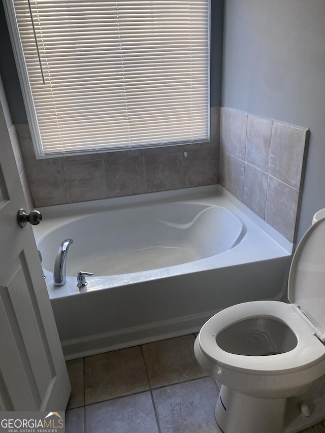 bathroom featuring tile patterned floors, a bathtub, and toilet