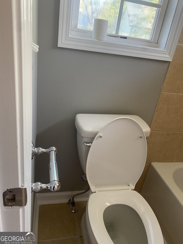 bathroom featuring tile patterned floors, toilet, and a bathing tub