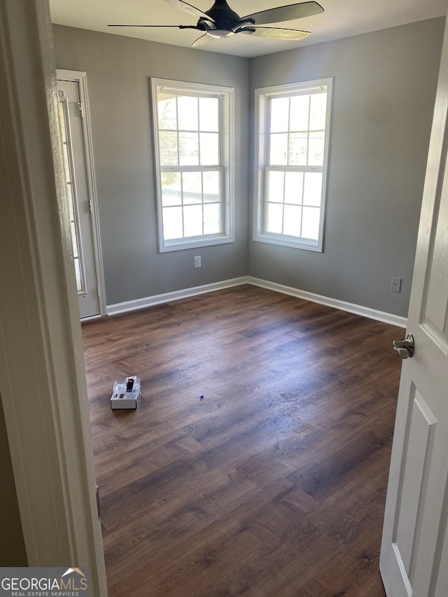 empty room with ceiling fan and dark wood-type flooring