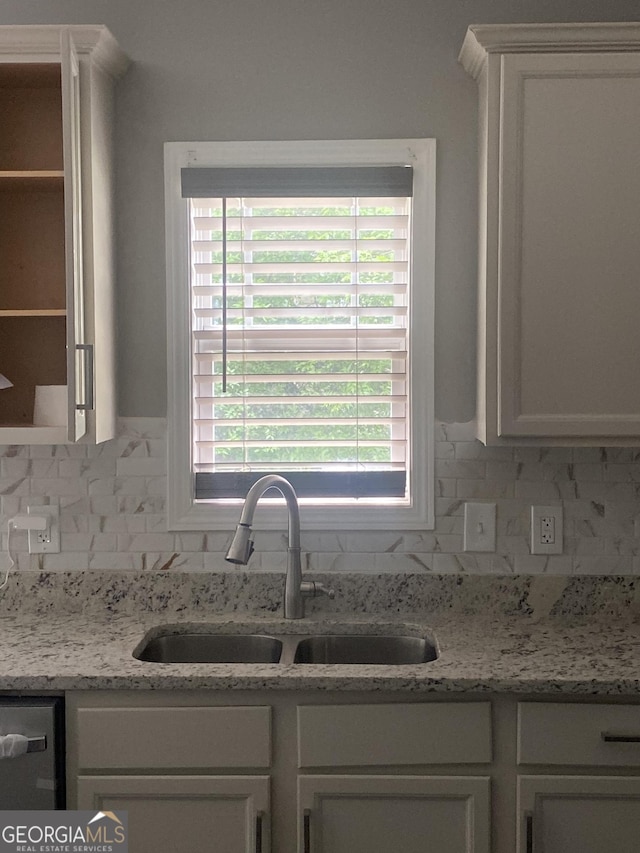 kitchen featuring white cabinets, light stone countertops, dishwasher, and sink