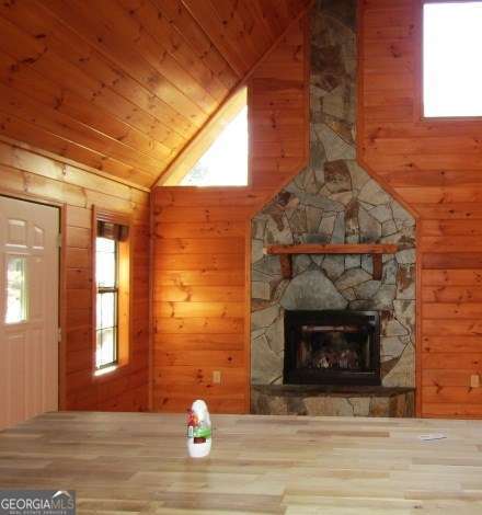 unfurnished living room featuring wood walls, a fireplace, and a wealth of natural light