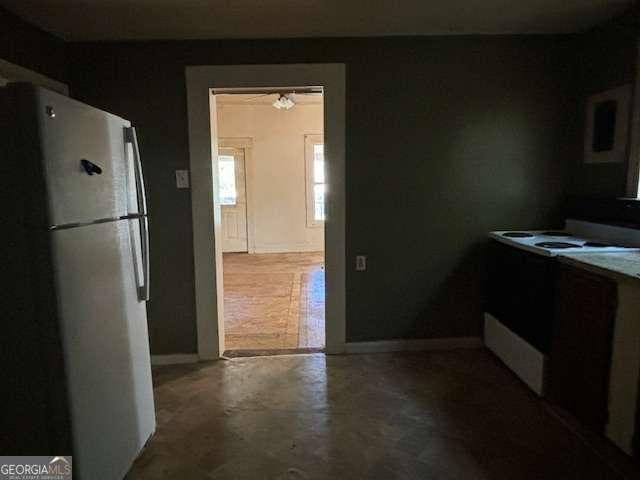 kitchen with white appliances and concrete flooring