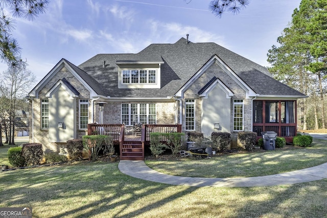 view of front of property with a front yard, a deck, and a sunroom