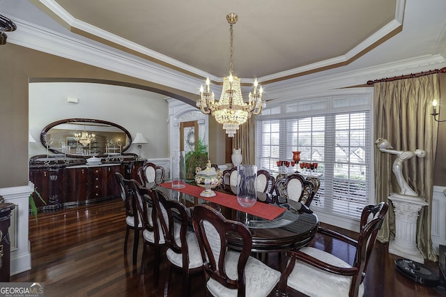 dining area featuring dark hardwood / wood-style flooring, crown molding, a tray ceiling, and an inviting chandelier