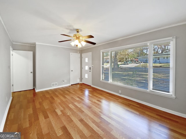 empty room with ceiling fan, crown molding, and light wood-type flooring