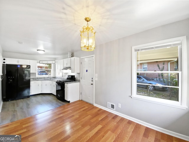 kitchen featuring black appliances, decorative light fixtures, a chandelier, hardwood / wood-style floors, and white cabinetry