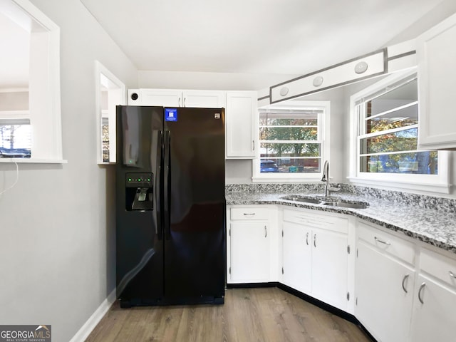 kitchen featuring a wealth of natural light, white cabinetry, sink, and black refrigerator with ice dispenser