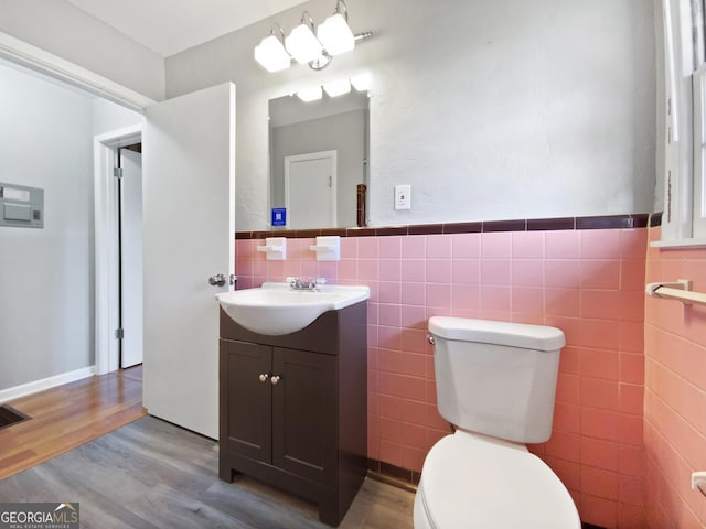 bathroom with vanity, toilet, wood-type flooring, and tile walls