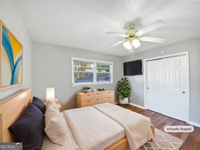 bedroom featuring a textured ceiling, a closet, ceiling fan, and dark wood-type flooring