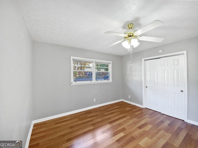 unfurnished bedroom with a closet, a textured ceiling, hardwood / wood-style flooring, and ceiling fan