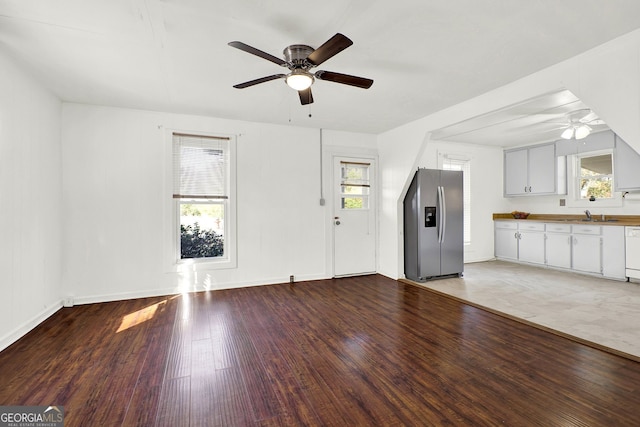 unfurnished living room with wood-type flooring, ceiling fan, and a healthy amount of sunlight