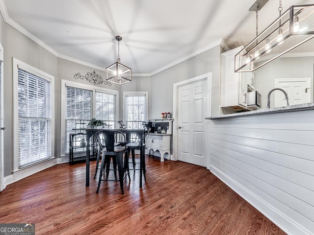 dining area featuring dark hardwood / wood-style flooring, crown molding, and an inviting chandelier