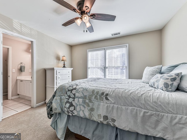 bedroom with ceiling fan, light colored carpet, and connected bathroom