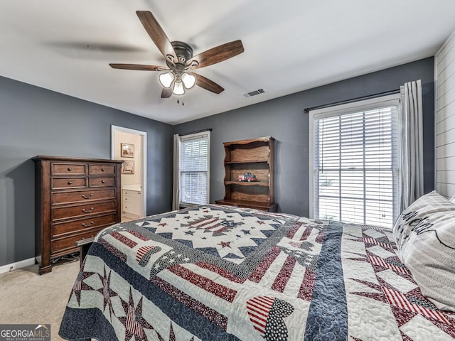 bedroom featuring multiple windows, connected bathroom, light carpet, and ceiling fan