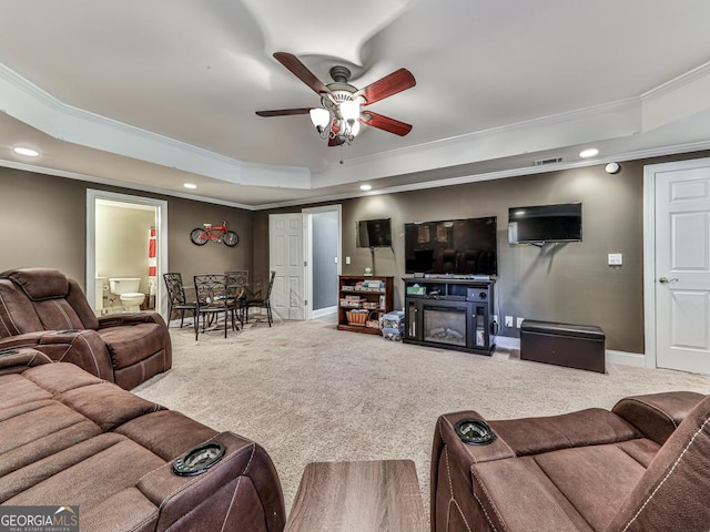 living room featuring ornamental molding, carpet flooring, ceiling fan, and a tray ceiling