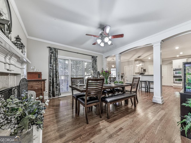 dining space with ceiling fan, wood-type flooring, decorative columns, and ornamental molding