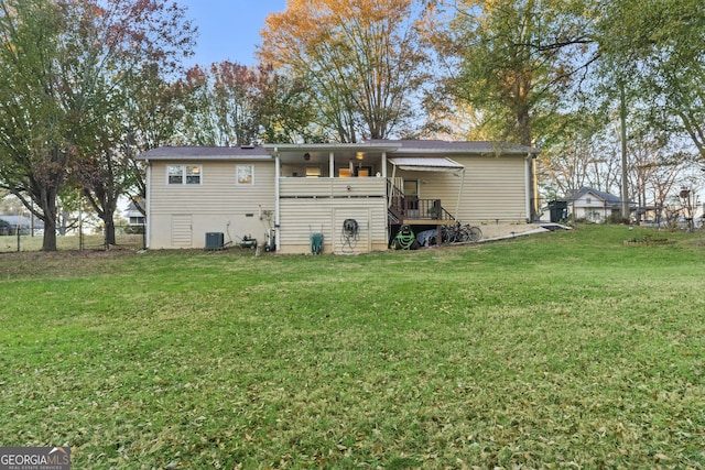 rear view of house with central AC unit and a yard