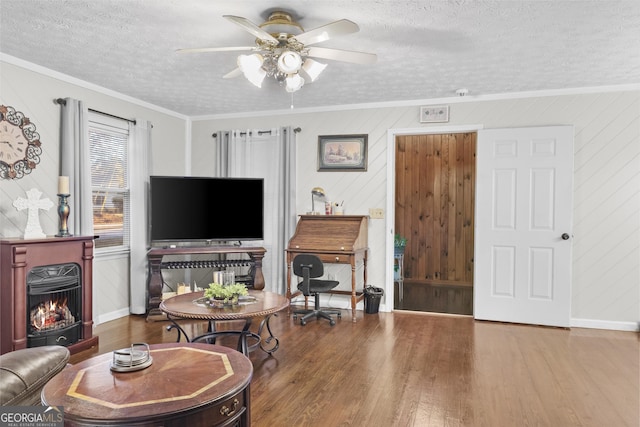 living room with crown molding, wooden walls, wood-type flooring, and a textured ceiling