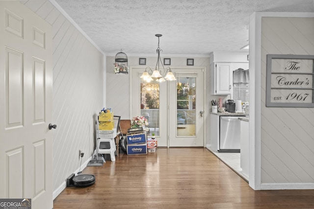 interior space with wood walls, crown molding, a textured ceiling, dark hardwood / wood-style flooring, and a chandelier