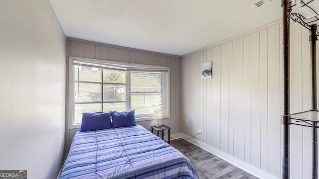 bedroom featuring hardwood / wood-style floors and wooden walls