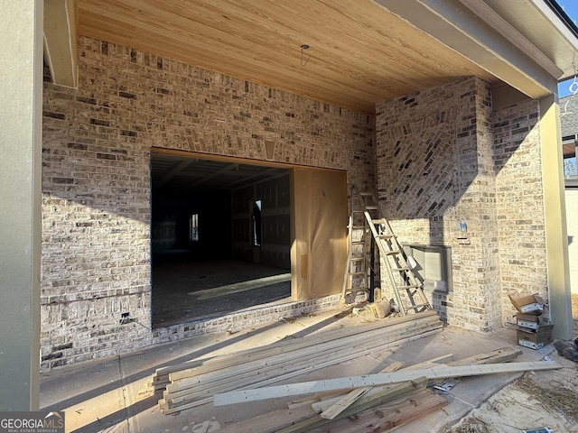 miscellaneous room with wood ceiling and brick wall