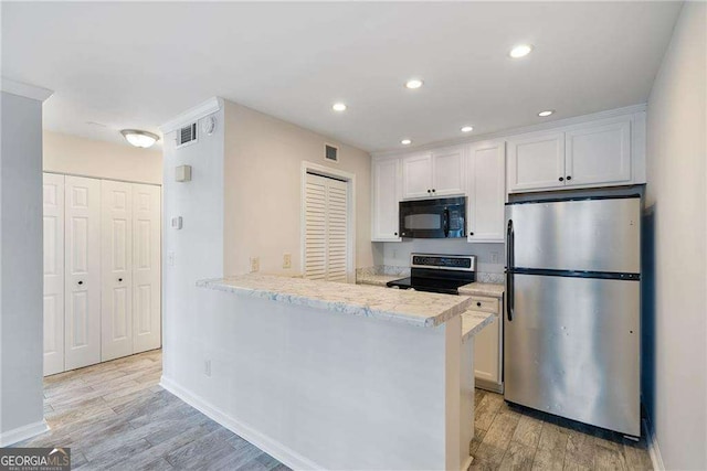 kitchen featuring recessed lighting, stainless steel appliances, a peninsula, white cabinets, and light wood-type flooring