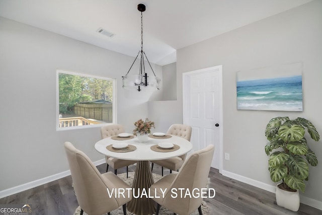 dining area with dark hardwood / wood-style flooring and an inviting chandelier