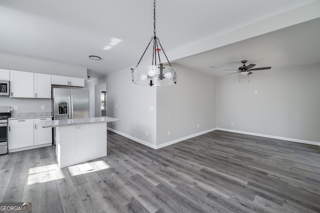 kitchen with dark hardwood / wood-style flooring, decorative light fixtures, white cabinets, ceiling fan with notable chandelier, and appliances with stainless steel finishes