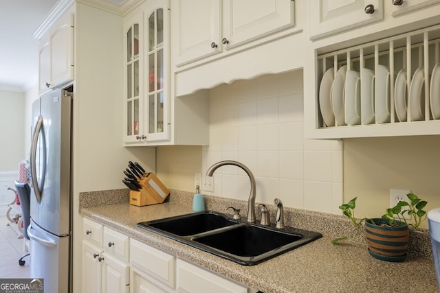 3798 Bermuda Run Dr, Valdosta, GA 31605 - kitchen featuring freestanding refrigerator, glass insert cabinets, crown molding, white cabinets, and tasteful backsplash