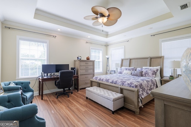 bedroom with light hardwood / wood-style flooring, a raised ceiling, ceiling fan, and ornamental molding