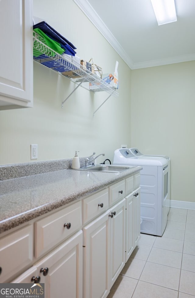 clothes washing area featuring cabinets, ornamental molding, sink, washer and dryer, and light tile patterned floors