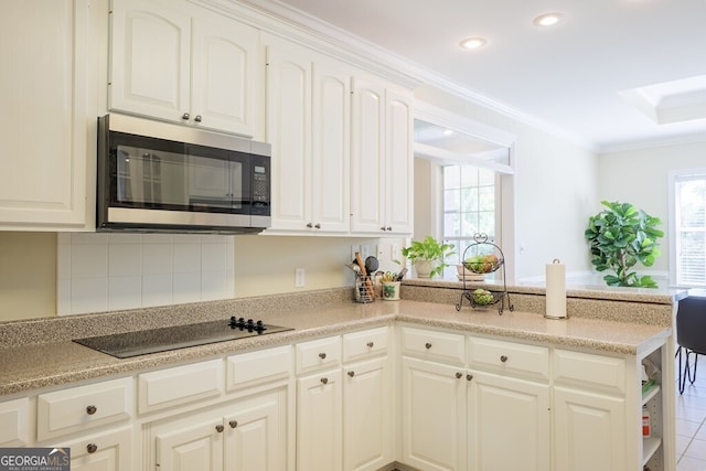 kitchen featuring backsplash, ornamental molding, black electric cooktop, tile patterned flooring, and white cabinetry