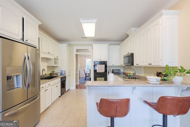 kitchen with black appliances, crown molding, kitchen peninsula, a kitchen bar, and white cabinetry