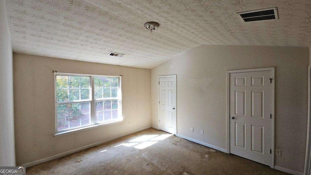 unfurnished bedroom with lofted ceiling and carpet flooring