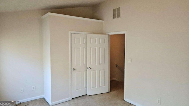 unfurnished bedroom featuring lofted ceiling and a closet