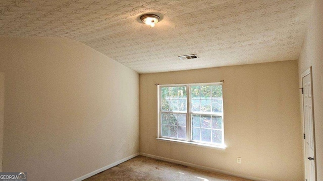 empty room featuring vaulted ceiling and a textured ceiling