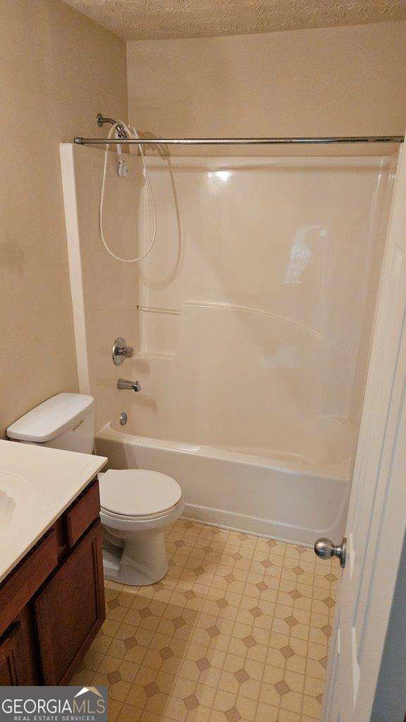 full bathroom with vanity, toilet, tub / shower combination, and a textured ceiling