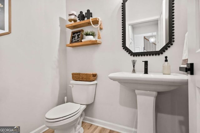 bathroom featuring baseboards, wood finished floors, and toilet