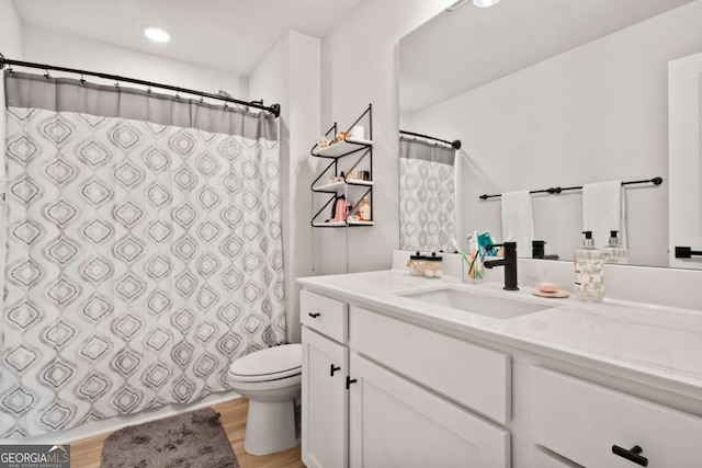 bathroom featuring toilet, recessed lighting, vanity, and wood finished floors