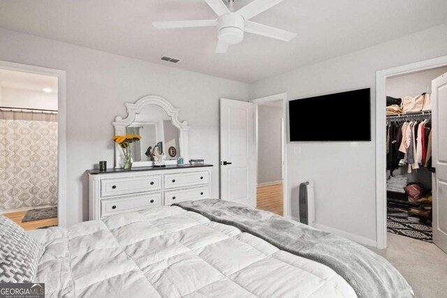 carpeted bedroom featuring ensuite bathroom, a closet, ceiling fan, and a spacious closet