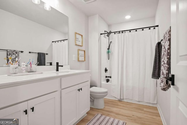 full bath featuring toilet, vanity, wood finished floors, shower / tub combo, and visible vents