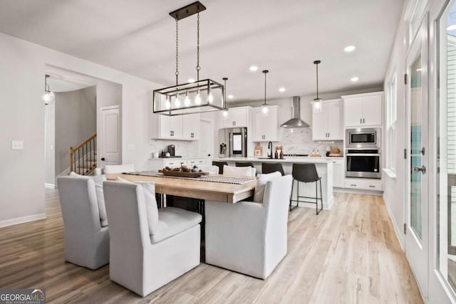 dining area with stairs, light wood-style flooring, baseboards, and recessed lighting