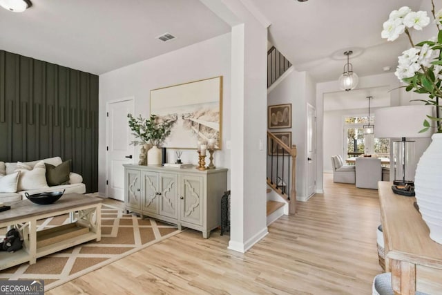 foyer entrance with light wood-style flooring, baseboards, stairs, and visible vents