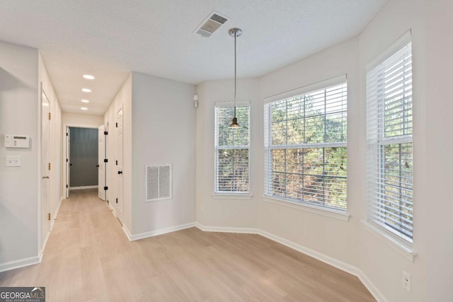 unfurnished dining area featuring light hardwood / wood-style floors and a textured ceiling