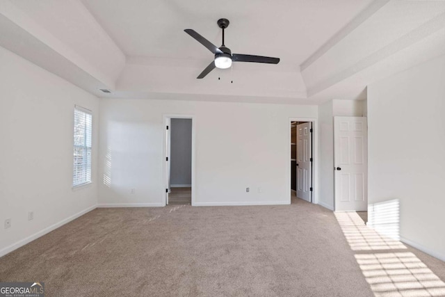 unfurnished room featuring ceiling fan, a raised ceiling, and light carpet