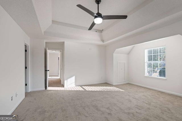 interior space featuring light carpet, a tray ceiling, and ceiling fan