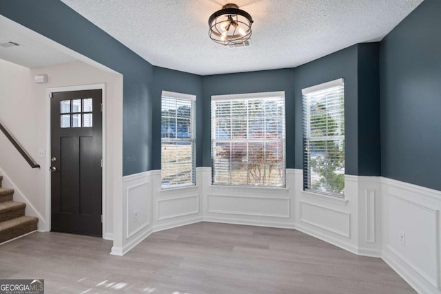 foyer with a textured ceiling, light hardwood / wood-style flooring, and plenty of natural light