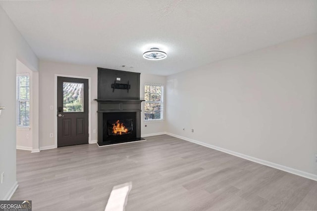 unfurnished living room featuring a large fireplace, plenty of natural light, and light hardwood / wood-style floors