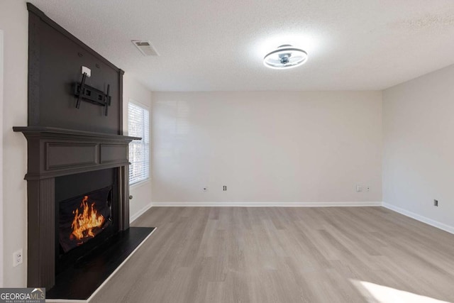 unfurnished living room featuring light hardwood / wood-style floors and a textured ceiling