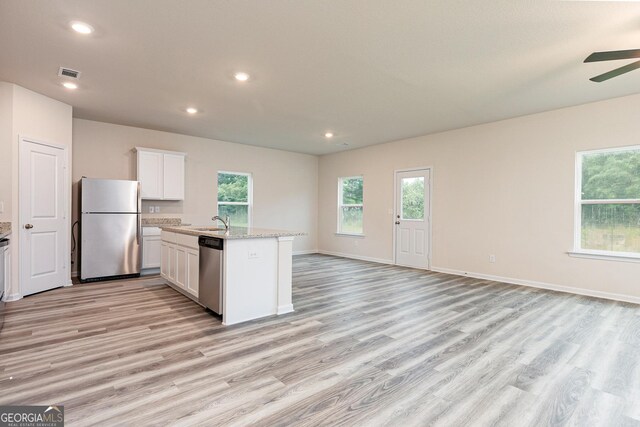 kitchen featuring sink, stainless steel appliances, an island with sink, light hardwood / wood-style floors, and white cabinets